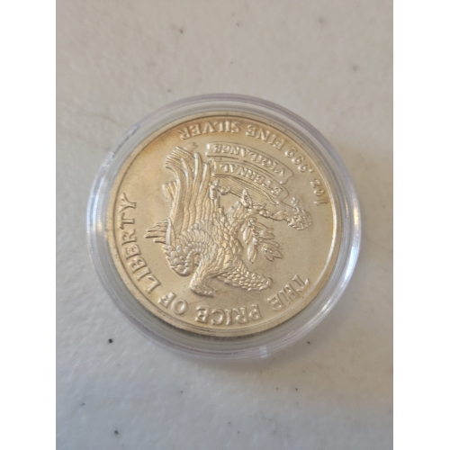 Silver coin with dragon design in a case.