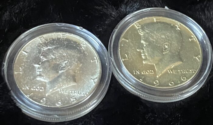 Two Kennedy half-dollar coins in protective cases.