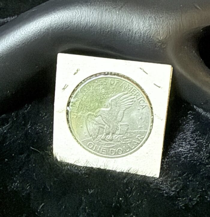 Silver American eagle dollar coin displayed on black surface.