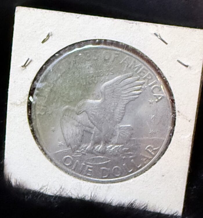 Silver one dollar coin with embossed eagle design.