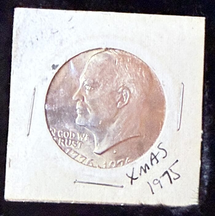 Eisenhower dollar coin in holder, marked Xmas 1975.