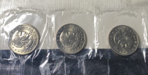 Three Susan B. Anthony dollar coins in plastic sleeves.