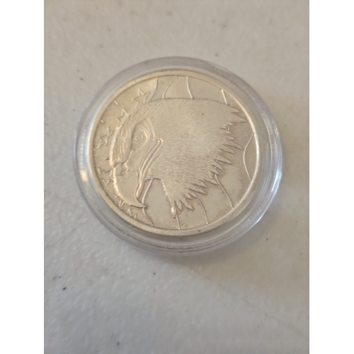 Silver coin with eagle design in case.