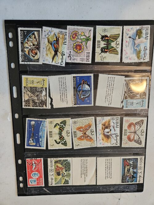 Collection of vintage Dubai postage stamps in album.