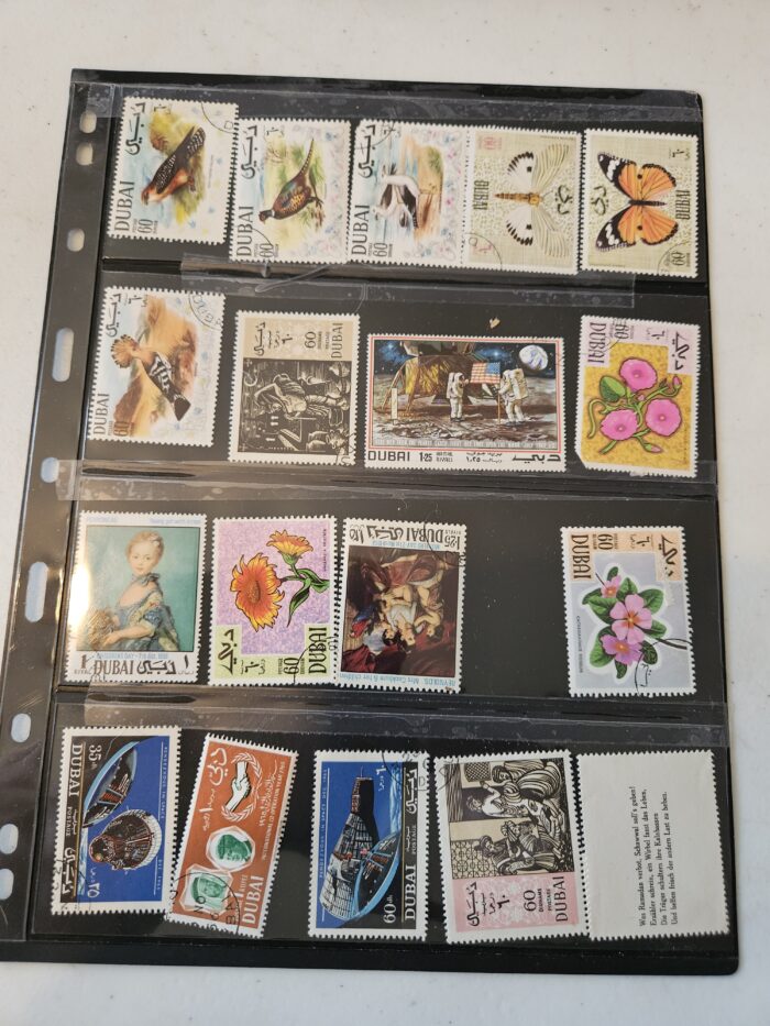 Collection of vintage Dubai postage stamps in album.