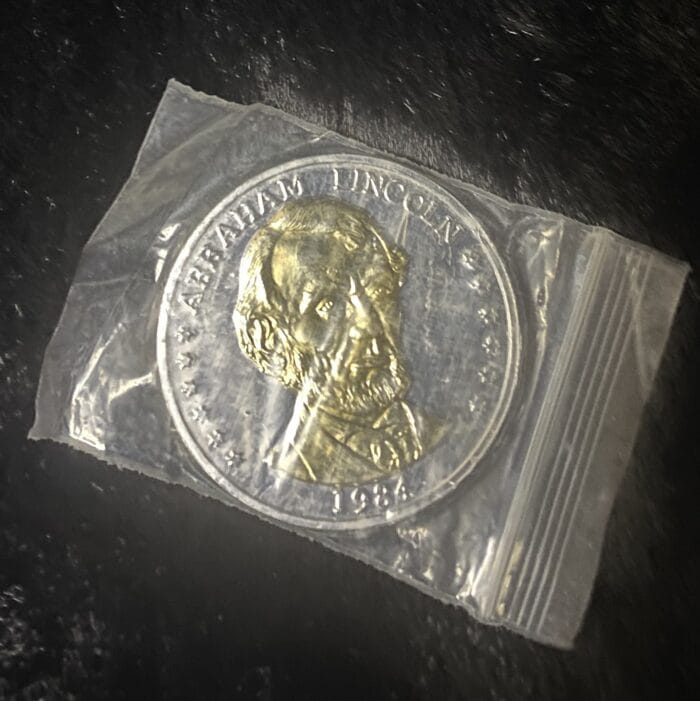 Abraham Lincoln gold coin in plastic bag.