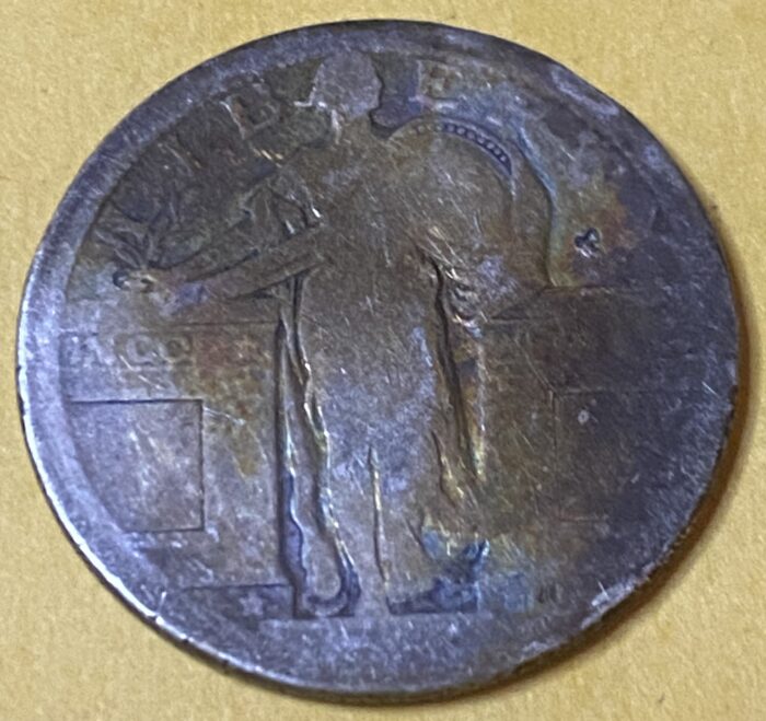 Old coin with worn design on yellow background.