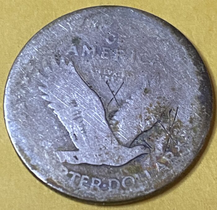 Old coin with eagle design on yellow background.